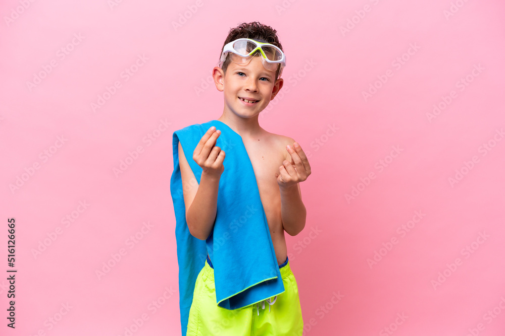 Little caucasian boy wearing a diving goggles isolated on pink background making money gesture Little caucasian boy wearing a diving goggles isolated on pink background making money gesture