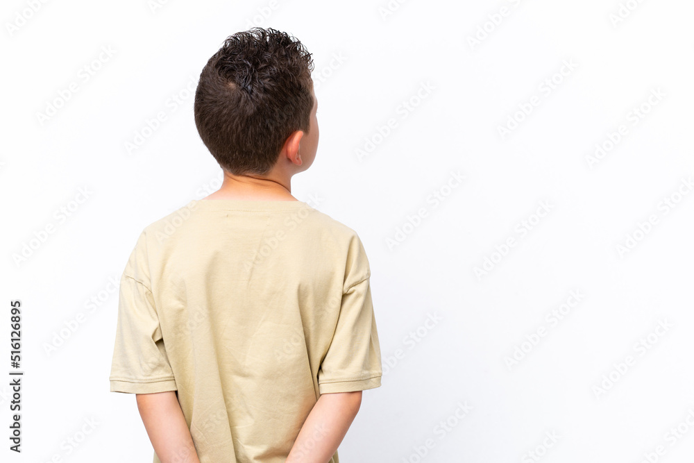 Little caucasian boy isolated on white background in back position and looking back