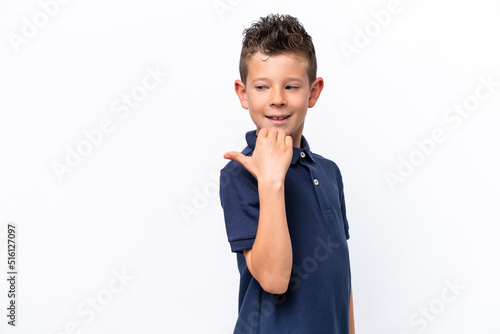 Little caucasian boy isolated on white background pointing to the side to present a product