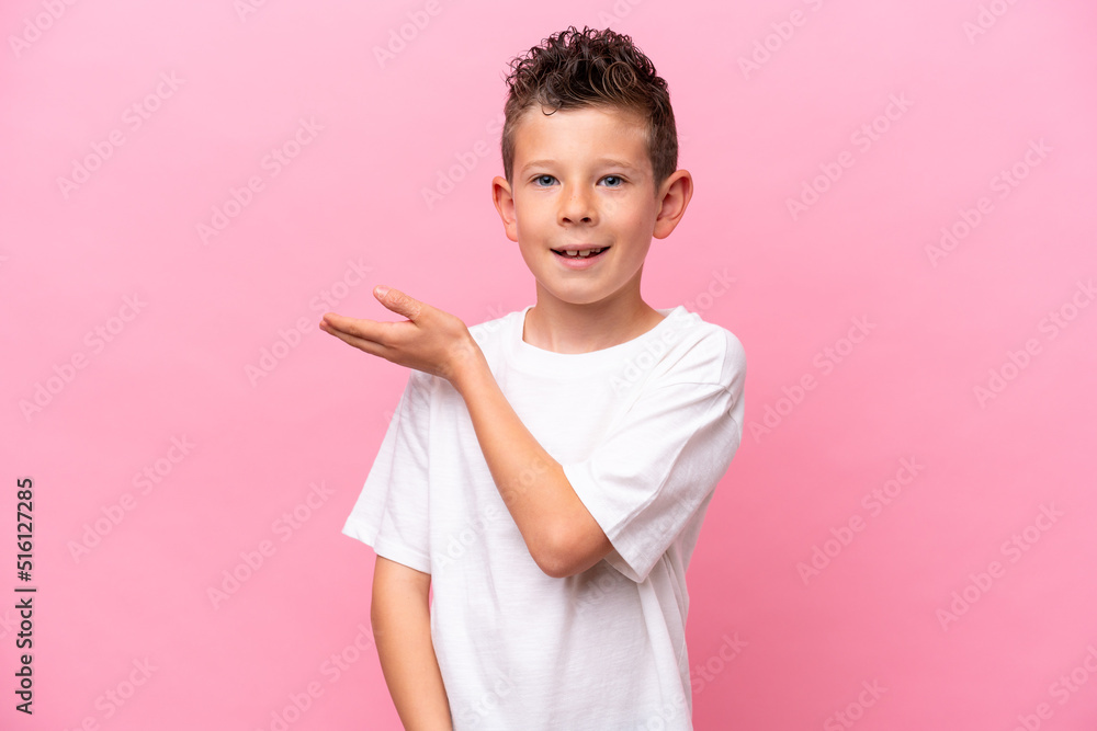 Little caucasian boy isolated on pink background presenting an idea while looking smiling towards Little caucasian boy isolated on pink background presenting an idea while looking smiling towards