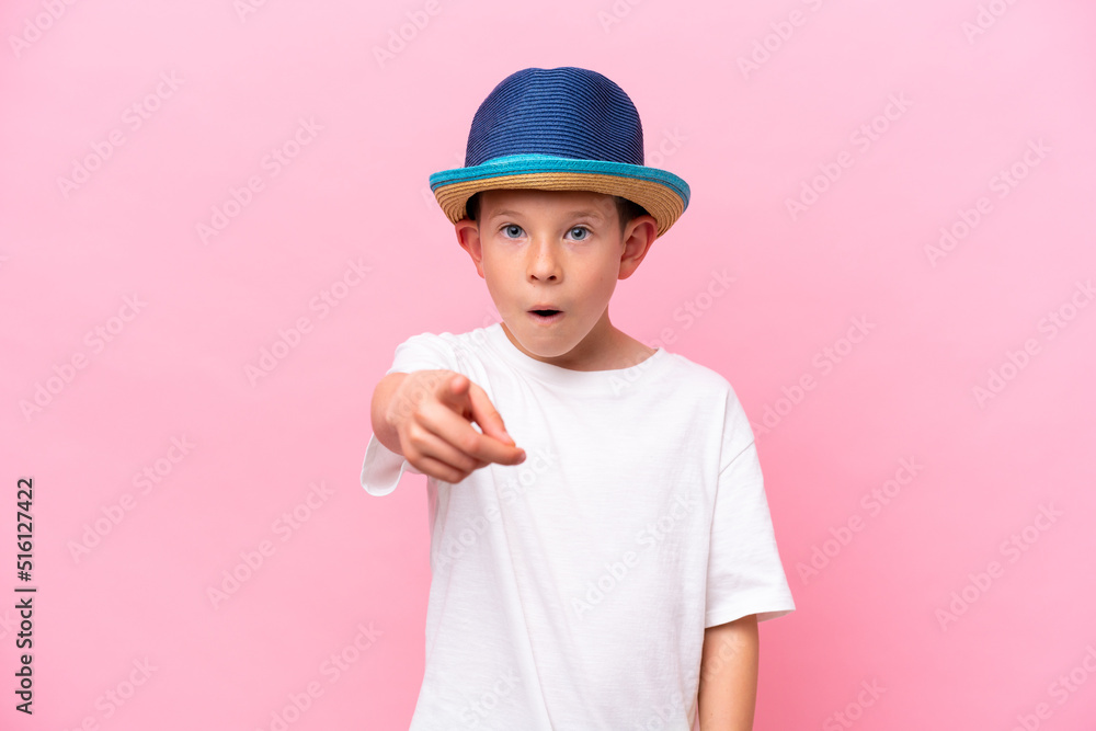 Little caucasian boy wearing a hat isolated on pink background surprised and pointing front Little caucasian boy wearing a hat isolated on pink background surprised and pointing front