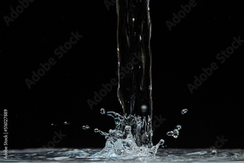 Water pours onto the surface of the water on a black background. Clean drinking water.