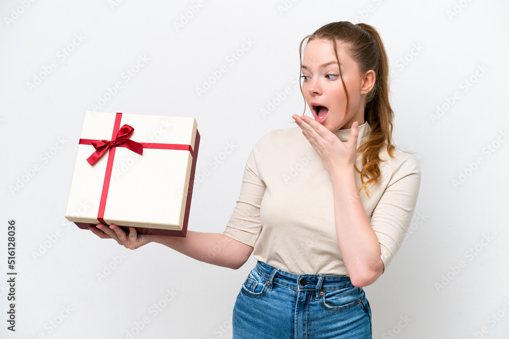 Young caucasian woman holding a gift isolated on white background with surprise and shocked facial expression Young caucasian woman holding a gift isolated on white background with surprise and shocked facial expression