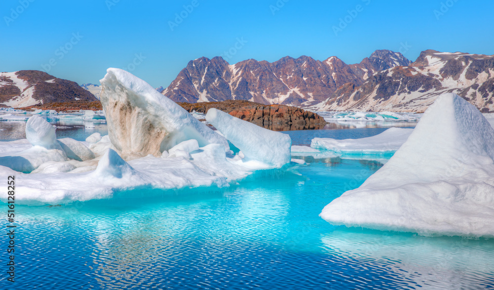 Fototapeta premium Melting icebergs by the coast of Greenland, on a beautiful summer day - Melting of a iceberg and pouring water into the sea - Greenland