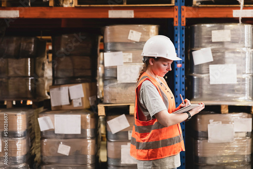 Female workers in safety helmet using scanner checking inventory stock at warehouse. Retail warehouse with full shelves of goods cardboard boxes, Product Distribution Delivery Center.