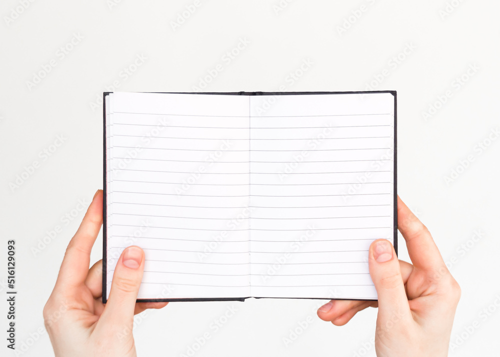female hands hold an open lined notebook with blank white pages. education, business concept female hands hold an open lined notebook with blank white pages. education, business concept