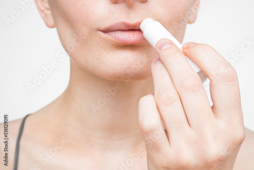 young woman applying moisturizing lip balm. lip care concept