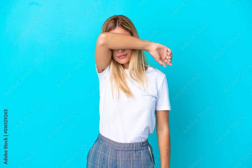 Blonde Uruguayan girl isolated on blue background covering eyes by hands Blonde Uruguayan girl isolated on blue background covering eyes by hands