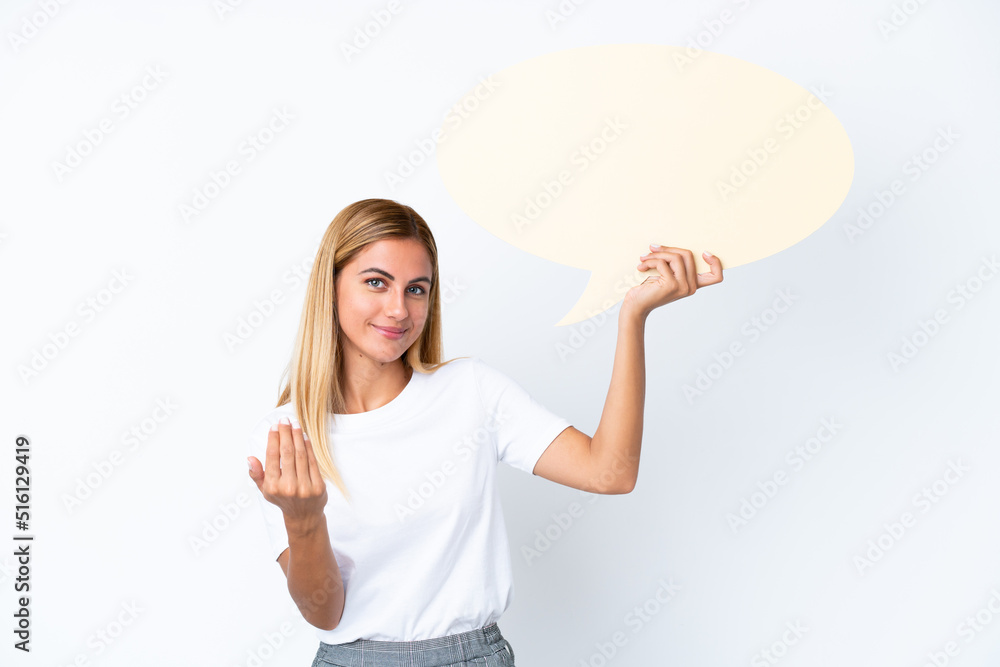 Blonde Uruguayan girl isolated on white background holding an empty speech bubble and doing coming gesture Blonde Uruguayan girl isolated on white background holding an empty speech bubble and doing coming gesture