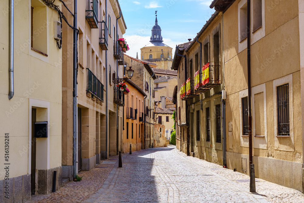 Narrow alley with old houses and view of the cathedral of Segovia in the background, Spain.