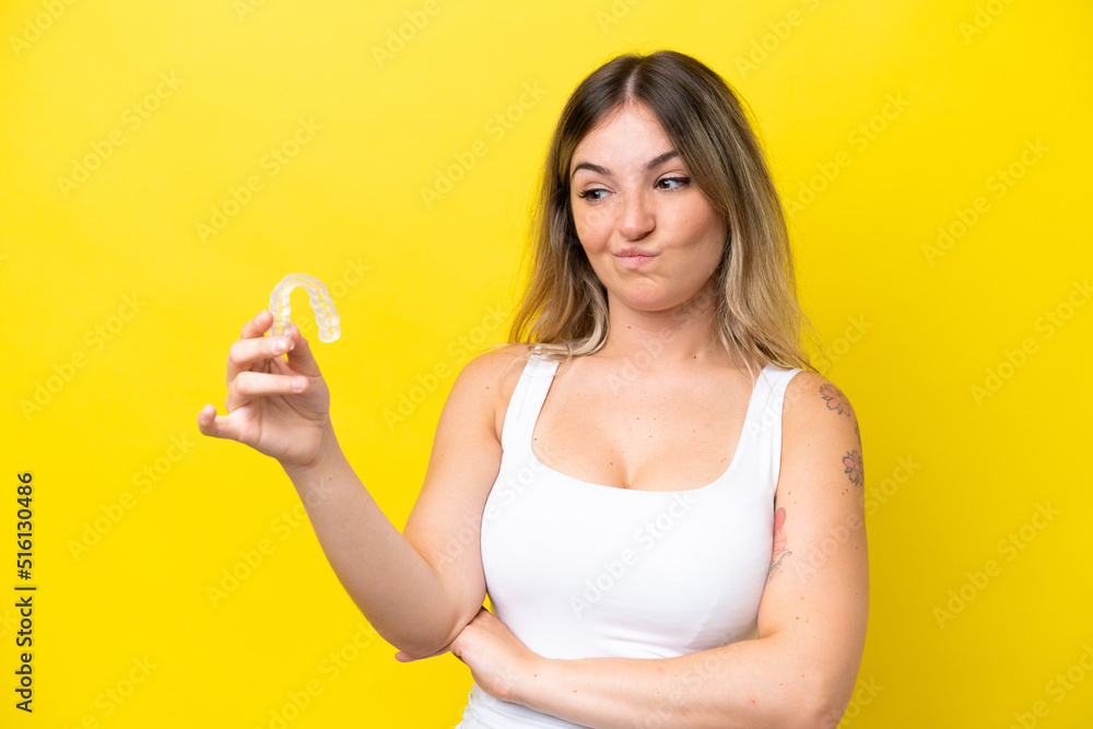 Young Rumanian woman holding envisaging isolated on yellow background with sad expression Young Rumanian woman holding envisaging isolated on yellow background with sad expression