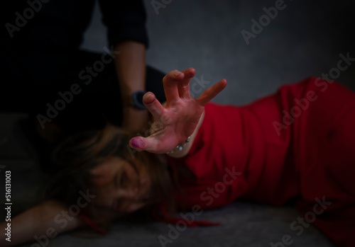 concept of violence against women,crime. bloody hand of female victims in red dress asking for help from being violence © Verin
