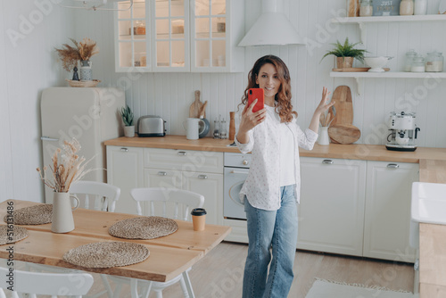 Billede på lærred Young hispanic woman boasting with her stylish kitchen