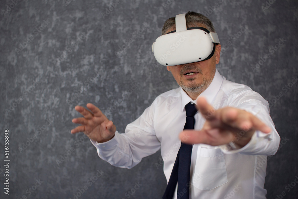 A man wearing virtual reality glasses. A businessman of Caucasian nationality with gray hair, dressed in a virtual reality headset, tie and white shirt. A man wearing virtual reality glasses. A businessman of Caucasian nationality with gray hair, dressed in a virtual reality headset, tie and white shirt.