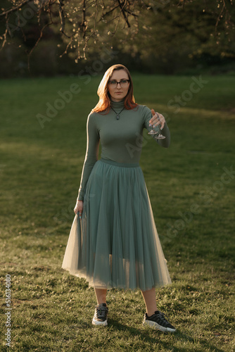 A full-length female redhead magician holds Reiki Tibetan Cymbals for chimes sound therapy. Session of a meditation healing in the park at sunset.