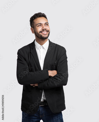 Portrait of handsome smiling young man with folded arms. Laughing joyful cheerful men with crossed hands studio shot. Isolated on gray background