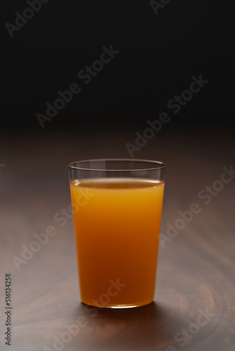 Fresh orange juice in thin glass on wooden table with copy space