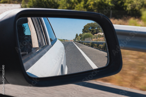 Road as seen from the rearview mirror of a car
