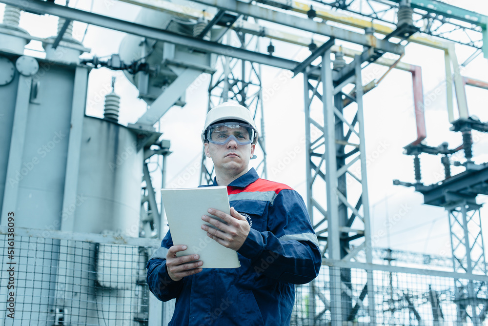 An energy engineer inspects the modern equipment of an electrical substation before commissioning. Energy and industry. Scheduled repair of electrical equipment.