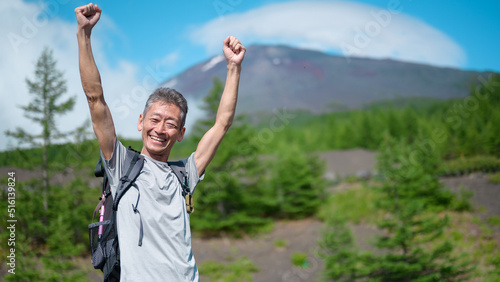富士山をバックに手を挙げる登山者 