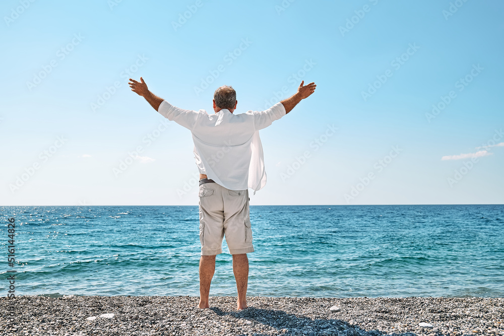 Happy middle-aged tourist man enjoying freedom with open hands on sea. Wellness, success, freedom and travel concept. Trip in summertime. Happy middle-aged tourist man enjoying freedom with open hands on sea. Wellness, success, freedom and travel concept. Trip in summertime.