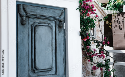 Fotografiet tiny wooden door at mediterranean or aegean typical house facade, blooming bouga
