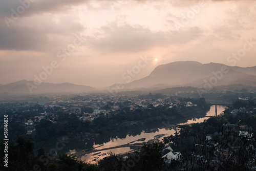 Luang Prabang, Laos - January 29th, 2020 : view from Mount Phousi on the city of Luang Prabang, the Mekong river and the surrounding mountains in the background at sunrise.