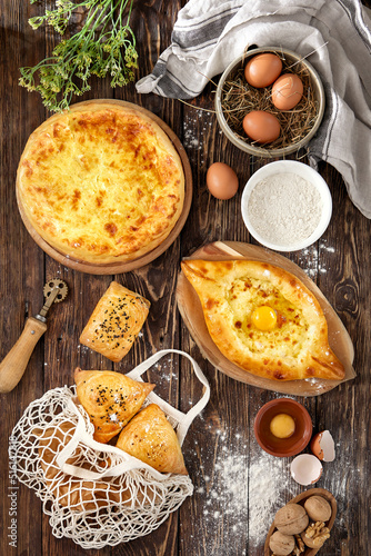 Traditional georgian pastry: ajarian and megrelian khachapuri, samsa. Georgian bakery composition. Pastry with cheese and eggs on wooden background in rustic style. Set of khachapuri with cheese.