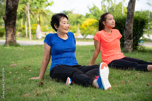 Asia senior woman and teenager rest sit on grass after walking or jogging exercise at park 