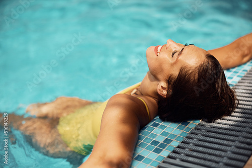 Young happy woman relaxing with eyes closed in swimming pool.