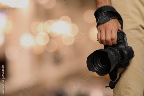 Professional photographer with modern camera and blurred background, space for text