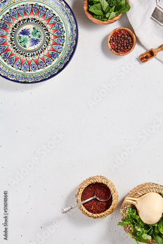 Oriental food background with empty uzbek plate and spices. Eastern cuisine background with copy space. Flat lay in eastern style with traditional dishes and fresh herbs. Uzbek food menu.