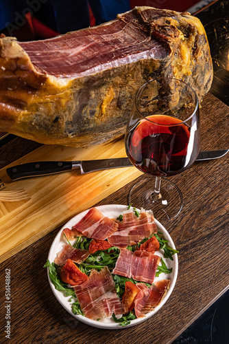 Iberian ham pata negra from Spain with red wine on wood background