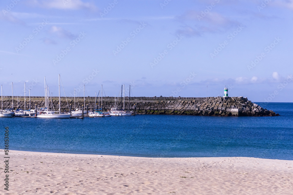 Breakwater with a lighthouse on it and moored yachts