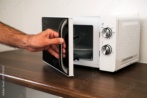 a man puts a plate in the microwave to warm up his food