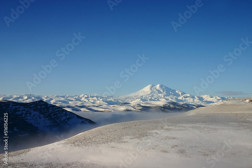 Elbrus is a high mountain. Dormant volcano. mountain covered with snow on blue sky background. Caucasus mountains. Fog and slopes