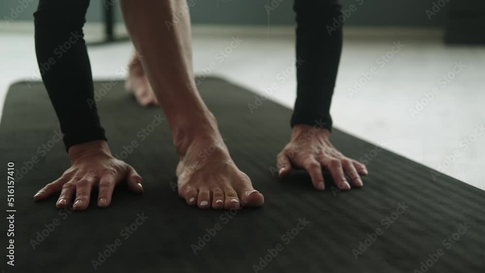 Yoga mat: An unidentified woman practices yoga in the studio, only her hands and feet are on the mat in the frame. Stretching: training on a sports mat. Close-up. Sports Equipment Yoga mat: An unidentified woman practices yoga in the studio, only her hands and feet are on the mat in the frame. Stretching: training on a sports mat. Close-up. Sports Equipment