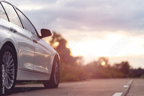 Behind a beautiful white car parked on a road with beautiful sunsets. with space for text. © PIPAT
