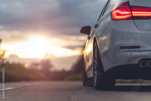 Behind a beautiful white car parked on a road with beautiful sunsets. with space for text.