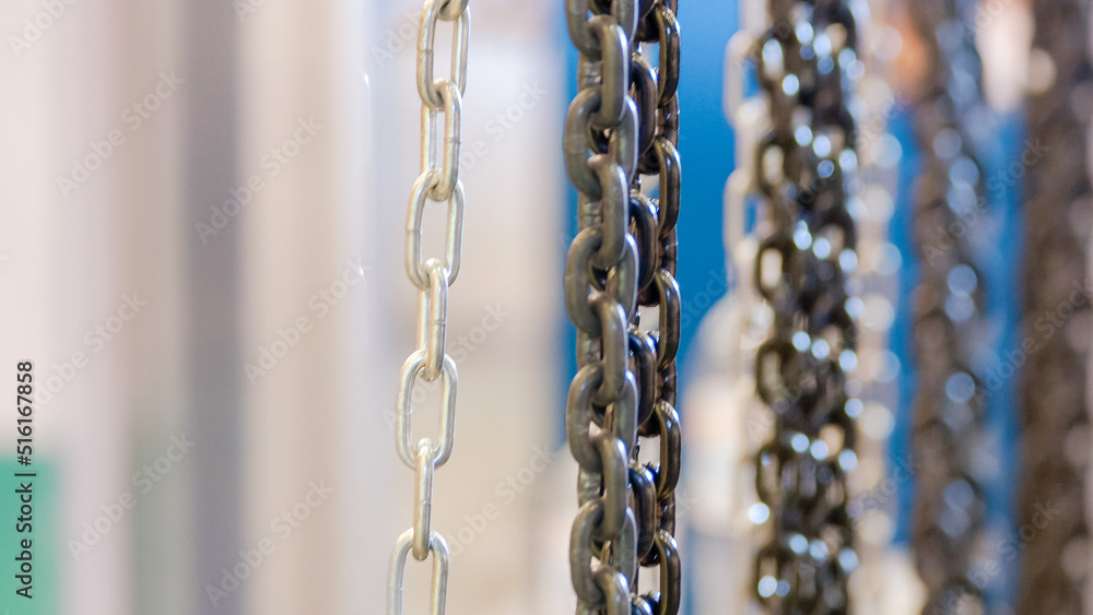 Close-up of various hanging strong metal chains. Chains of different size and color.