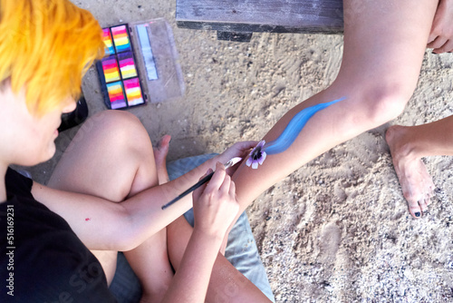 Top view of an artist painting the leg of a woman on the beach