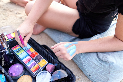 Artist trying out shades of color on her skin during a body paint session.