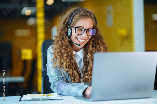 Female customer service representative in a headset is consulting clients online. Call center and business people concept photo