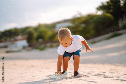 Trash on the beach. Scavengery. Child with mother collects plastic, garbage on the beach by the sea. Environmental pollution. Ecological problem. photo