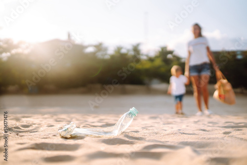 Trash on the beach. Scavengery. Child with mother collects plastic, garbage on the beach by the sea. Environmental pollution. Ecological problem. photo