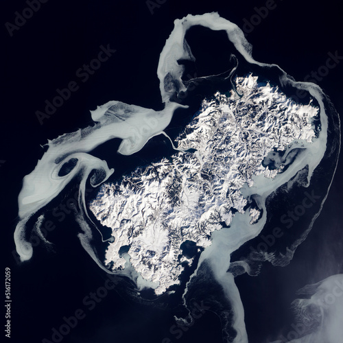 Sea ice swirling around Shikotan Island at the southern end of the Kuril chain, Top view of a volcanic island. Aerial view of winter sea ice texture. Elements of this image furnished by NASA. photo