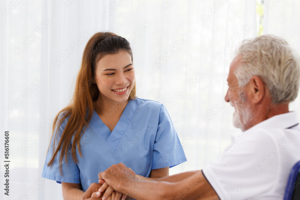 female doctor helping care holding hands to encourage talk Caucasian older man, older adult, patient in a wheelchair female doctor helping care holding hands to encourage talk Caucasian older man, older adult, patient in a wheelchair