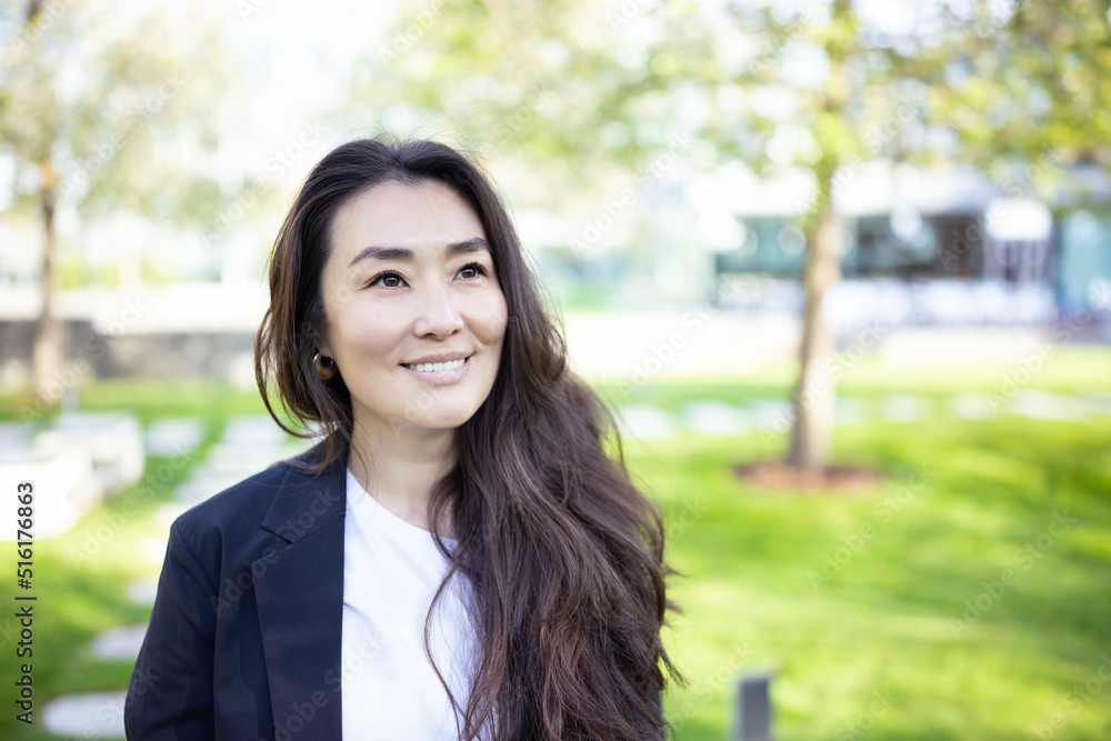 Asian confident business woman in suit smiling, looking up to the bright future of her career opportunities. Job, work aspirational banner, spring background of office center with trees. Business Asian confident business woman in suit smiling, looking up to the bright future of her career opportunities. Job, work aspirational banner, spring background of office center with trees. Business