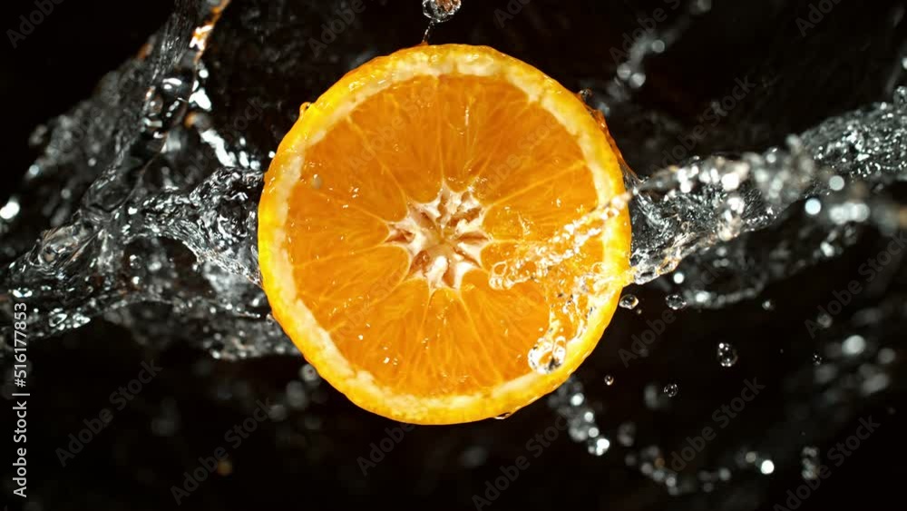 Super Slow Motion of Orange Slice With Water Splashes. Rotating Slice of Orange with Splashing Water Around. Isolated on Black Background. Filmed on High Speed Cinema Camera, 1000 Fps. Super Slow Motion of Orange Slice With Water Splashes. Rotating Slice of Orange with Splashing Water Around. Isolated on Black Background. Filmed on High Speed Cinema Camera, 1000 Fps.