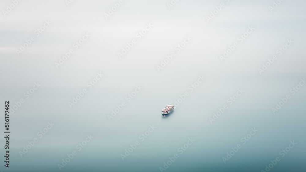 Fototapeta premium small cargo container ship floating in sea motion blur aerial view